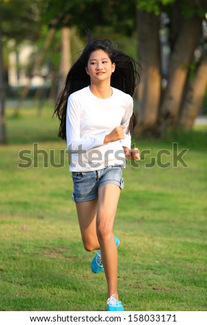 Female jogger. Fit young Asian woman jogging  park smiling happy running and enjoying a healthy outdoor lifestyle. Fitness runner girl in autumn forest with fall foliage. Mixed race Asian Caucasian.