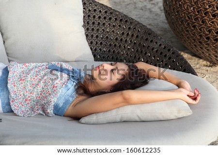 Relaxing woman sitting comfortable in sofa lounge chair smiling happy looking at camera. Resting beautiful young multicultural asian caucasian girl in her 30s .