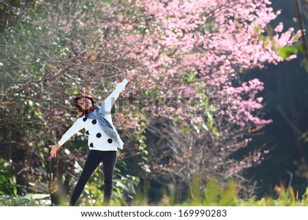 woman happy in free freedom pose with arms raised up towards the sky with smiling cheerful, elated expression of happiness. Beautiful girl in colorful of Cherry blossom , sakura flower forest outdoor