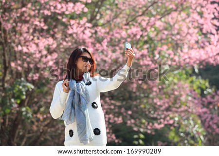 woman happy in free freedom pose with arms raised up towards the sky with smiling cheerful, elated expression of happiness. Beautiful girl in colorful of Cherry blossom , sakura flower forest outdoor