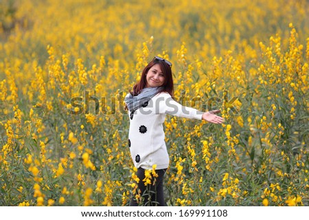 woman happy in free freedom pose with arms raised up towards the sky with smiling cheerful, elated expression of happiness. Beautiful girl in colorful of yellow blossom ,  flower forest outdoor