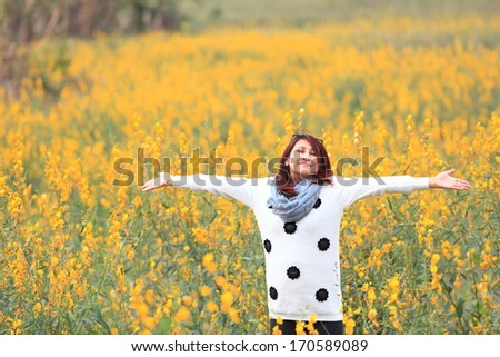 woman happy in free freedom pose with arms raised up towards the sky with smiling cheerful, elated expression of happiness. Beautiful girl in colorful of yellow blossom , flower forest outdoor