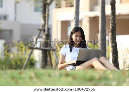 note book computer. Relaxed young  teenage in garden smiling content, happy and reading on tablet pc at home in garden. Lifestyle image of beautiful mixed Asian Caucasian girl relaxing smiling happy