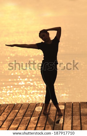 Yoga woman in serene sunset . Meditation and balance exercise at sunrise or sunset with female yoga instructor exercising outside in nature.