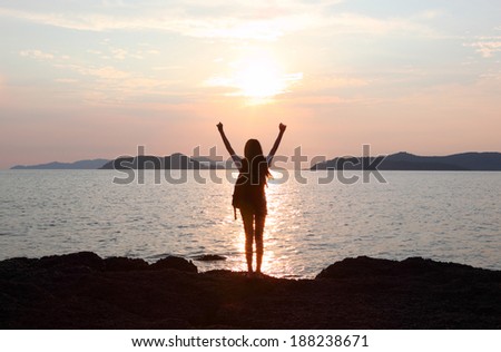 Free woman enjoying freedom feeling happy at beach at sunset. Beautiful serene relaxing woman in pure happiness and elated enjoyment with arms raised outstretched up. Asian Caucasian female model.