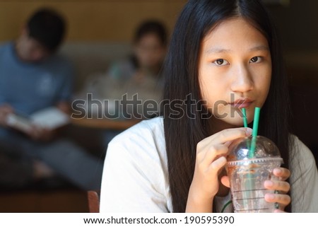 Cafe city lifestyle woman drinking coffee sitting indoor in trendy urban cafe. Cool young modern mixed race Asian Caucasian female model in her 15s.