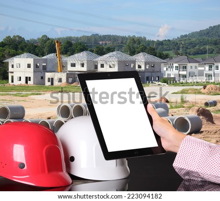 engineer working table plan, home model and writing tool equipment against building construction crane