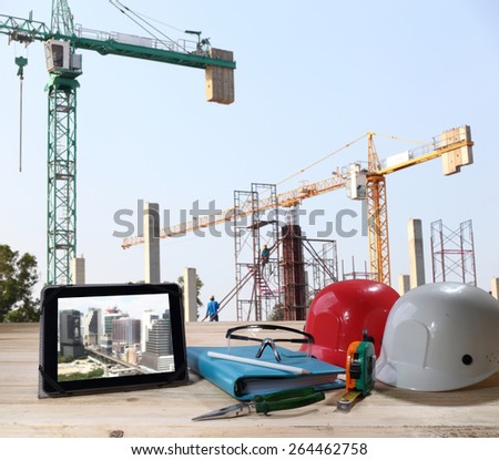 file of safety helmet and safety glasses on wood table in front of building construction background