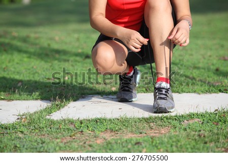 Running shoes - closeup of woman tying shoe laces. Female sport fitness runner getting ready for jogging outdoors on forest path in spring or summer.