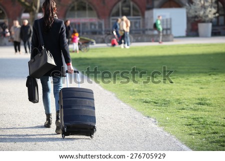 Beautiful woman with suitcases crossing the street in a big city.Beautiful woman  on a street and holding a suitcase. young woman with long legs in a urban setting