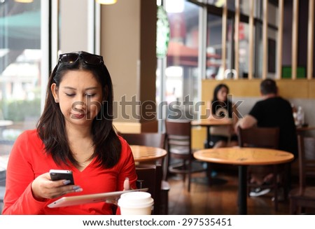Happy entrepreneur working with a phone and tablet in a coffee shop in the street