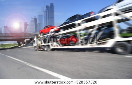 The trailer transports cars on highway with big city background