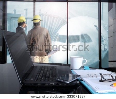 Office workplace with laptop and smart phone on table and  blurred background of Cabin of plane in air port