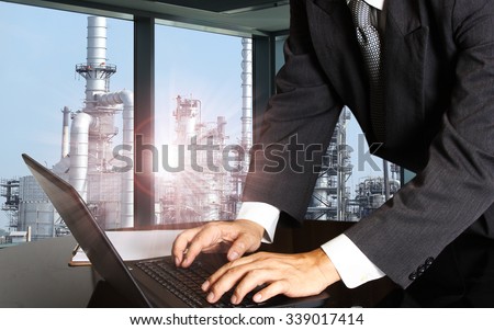 success businessman using computer laptop with oil refinery industry  of heavy industry background
