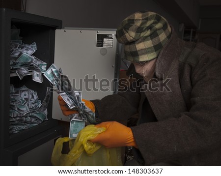 A thief wearing a mask steals money from the safe