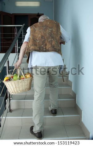 Elderly man rises up the stairs with a basket of fruit