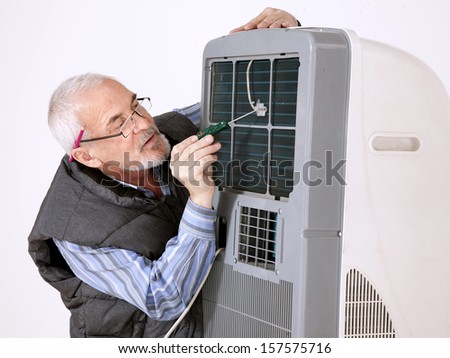 gray-haired man in glasses repairing air conditioning