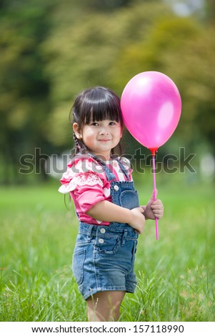 Asian little girl playing balloon in the garden