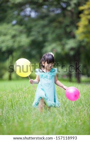 Asian little girl playing balloon in the garden