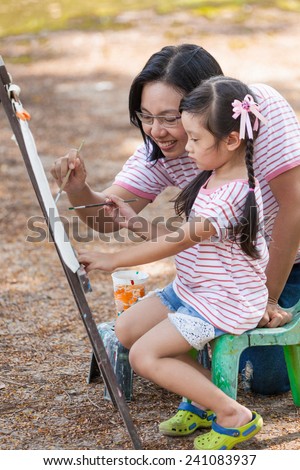 Asian mother and daughter enjoy painting in garden