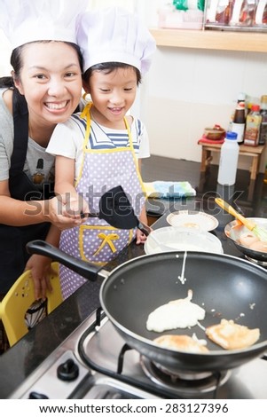 Asian mother teaching daughter making pancake