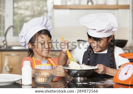 Little asian girls stiring wheat flour and egg