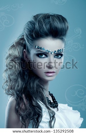 glamorous portrait of young woman with extravagant make-up on a blue background with patterns
