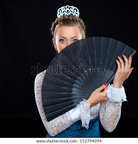 portrait of a beautiful young woman with a fan who dances flamenco on a black background.