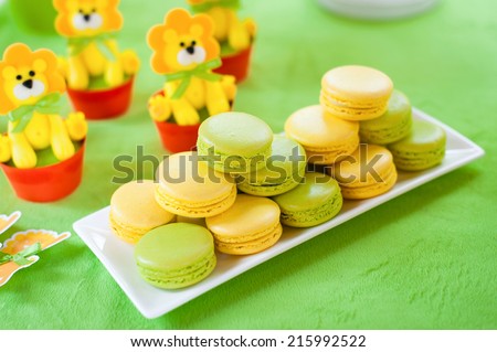 Yellow and green  tasty macaroni cookies and other cakes on the plate. Candy bar. Children\'s birthday.