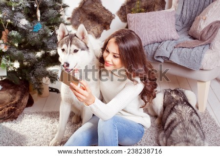 Young beautiful smiling brunette woman with phone in hand and dogs in a Christmas setting.Husky.