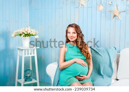 young beautiful pregnant woman in a dress in a marine interior