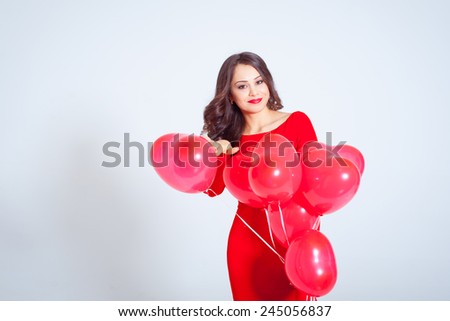 Beautiful young woman in a long red dress with balloons in the form of heart in his hands. Valentine\'s Day.