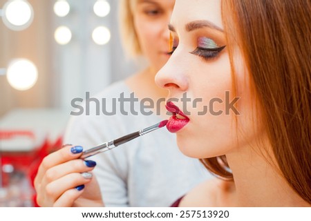Woman applying make up for a beautiful woman near mirror