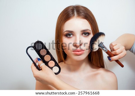 Makeup stylist applying make up for a beautiful woman