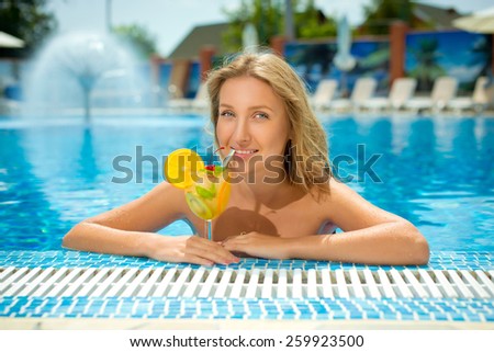 Young beautiful woman in the pool with a cocktail. Summer. Model.