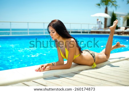 Beautiful young smiling woman with long hair in a bathing suit on the beach. Clean skin.