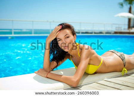 Beautiful young smiling woman with long hair in a bathing suit on the beach. Clean skin.