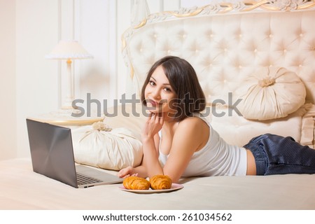 Young beautiful woman lying on the couch with a laptop .