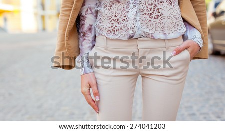 Detail of a beautiful young woman in trousers and high-heeled shoes posing in the city streets