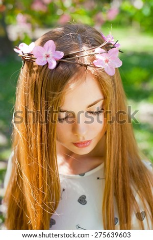 Young beautiful woman wearing a crown of barbed wire with flowers in the garden.