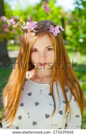 Young beautiful woman wearing a crown of barbed wire with flowers in the garden.