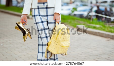 Detail of a beautiful young woman in pants and high-heeled shoes posing in the city streets . Fashion .