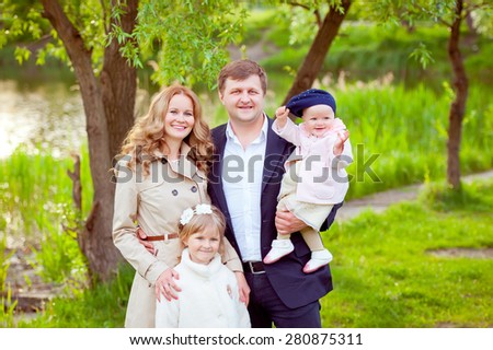 Young beautiful family on a walk in the park near the river. Four. Mother, father and two daughters.