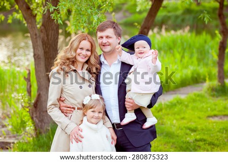 Young beautiful family on a walk in the park near the river. Four. Mother, father and two daughters.