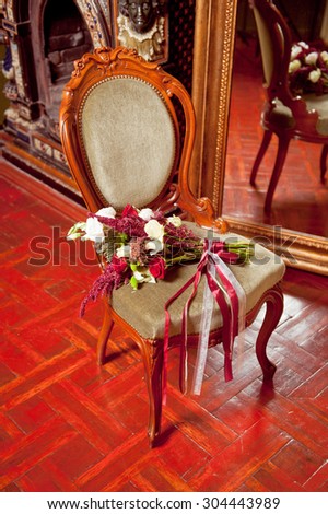 Beautiful wedding bouquet lying on the antique chair . Vintage interior .