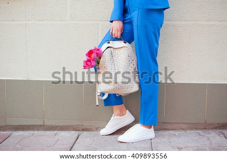 Fashionable young woman in blue suit and white sneakers on the city streets. Fashion. Backpack. Shawl.