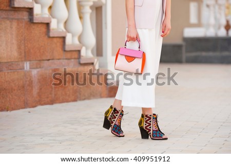 Fashionable young woman in white clothes with a handbag on the city streets .