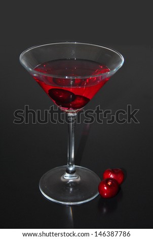 cocktail glass with two cherries on black background