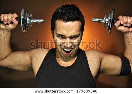 aggressive athlete training with dumbbells in gym