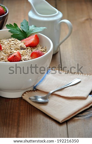 bowl of cereal with milk and strawberries on wooden table